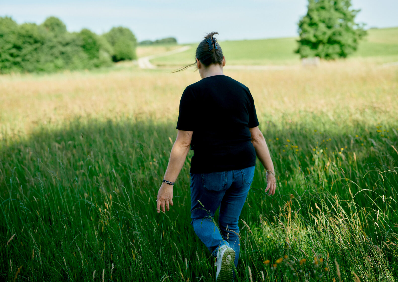 Frau geht achtsam einen Feldweg entlang