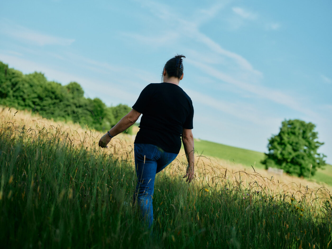 Mara Barrenscheen geht durch eine hohe Sommerwiese